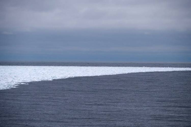 A small band of sea ice curves into open ocean waters.